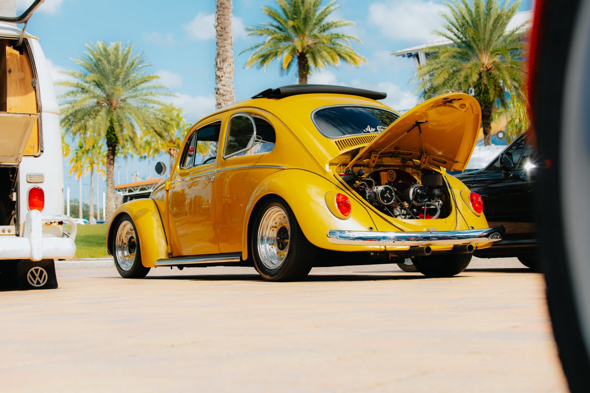 Yellow classic Volkswagen Beetle with rear engine hood open at a Florida car gathering